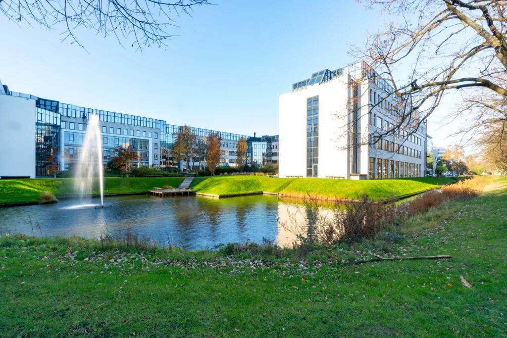 Modern kantoorgebouw aan de De Bruyn Kopsstraat met vijver en fontein op de voorgrond.